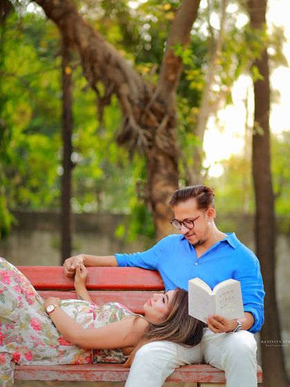 A romantic and creative pose on a park bench. The husband-to-be reads to his partner, creating a sweet and story-like image.