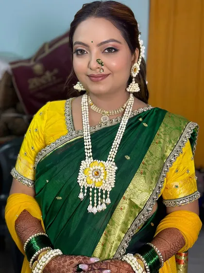 A smiling bride ready for her Haldi ceremony, showcasing her fresh makeup and traditional floral accessories.