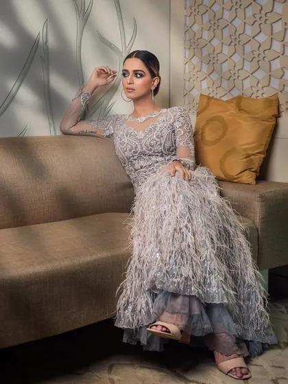 A sophisticated portrait of influencer Jumana Khan, ready for a Filmfare event. The focus is on the intricate details of her feathered gown and the glamorous makeup.
