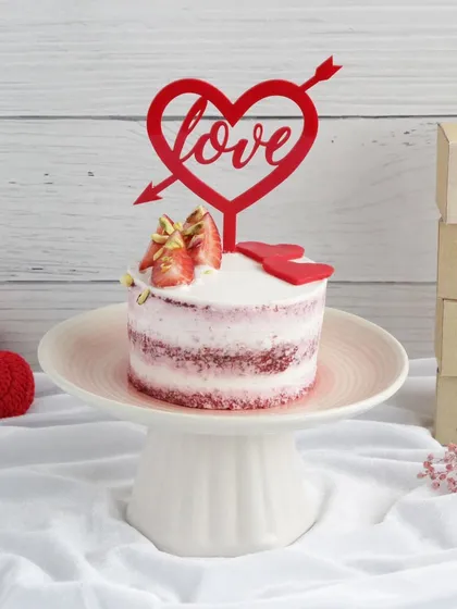 A naked red velvet cake for Valentine's Day, offering a rustic yet romantic look with fresh strawberries and a "Love" topper.