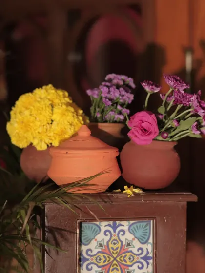 A close-up of a rustic decor element, featuring colorful flowers in earthy terracotta matkas. This simple arrangement adds a touch of traditional charm.