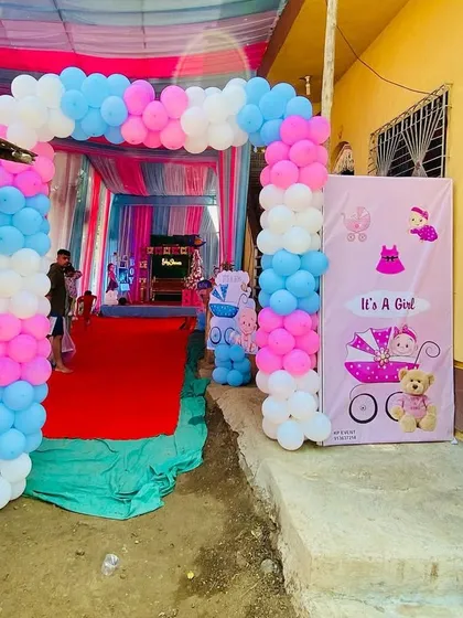 The entrance to a home baby shower, featuring a gender reveal theme with a pink and blue balloon arch and banners.