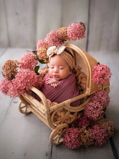 So cozy in her little floral carriage. I have a wide variety of props like this beautiful rattan wagon to create unique and adorable setups for your newborn's first photoshoot.