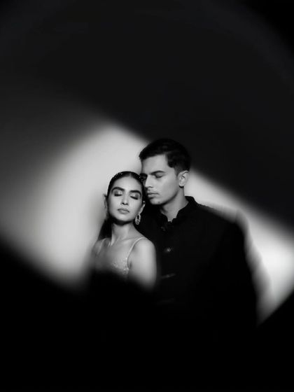 An artistic black and white couple portrait, using a spotlight effect to create an intimate and dramatic mood.