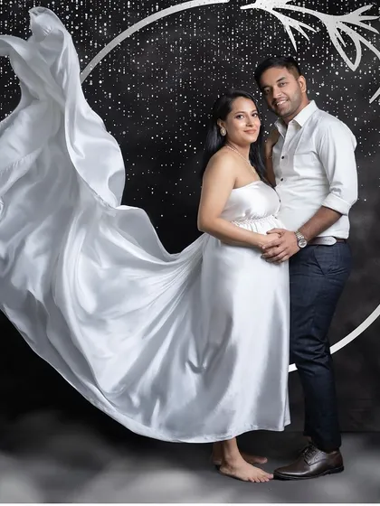 A creative couple's portrait using our starry night backdrop and a dramatic fabric toss. This style adds a touch of magic and fantasy to your maternity photoshoot.
