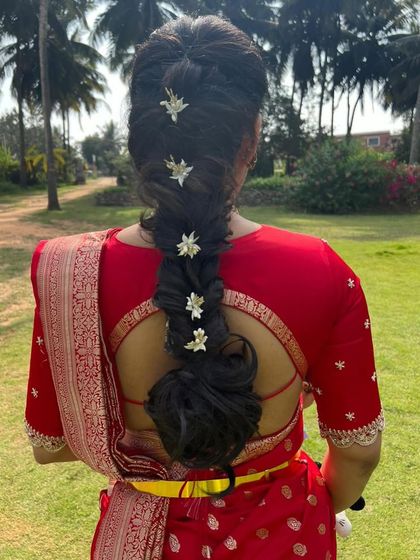 A back view of Amulya's red ensemble, showcasing her beautiful hairstyle and the elegant cut of the blouse.