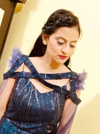 A close-up of the unique neckline and shoulder details on this sequined teal gown. The sheer sleeves and feather accents are beautiful touches.