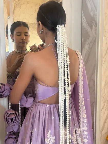 A beautiful shot of the client looking in the mirror, showing off her stunning pearl-adorned braid. It's a moment of quiet elegance before the event.