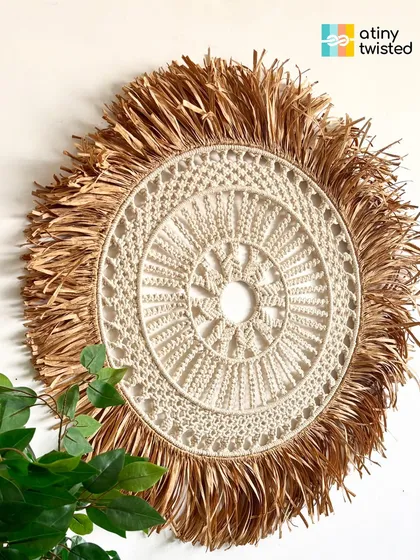 This large, round wall hanging features a detailed macramé mandala at its center, framed by a beautiful, wild raffia fringe. It's a true celebration of natural materials and handmade artistry.
