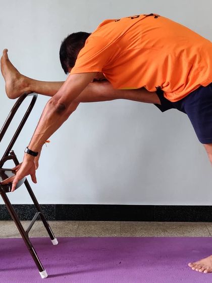 Utthita Hasta Padangusthasana (Extended Hand-to-Big-Toe Pose) using a chair for leg support. This helps to work on hamstring flexibility while maintaining a stable, upright torso.