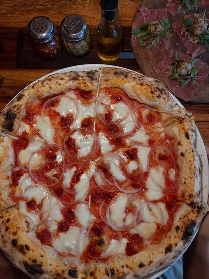 Another angle of our Goan Sausage pizza, with our house-made chili oil and other condiments in the background.