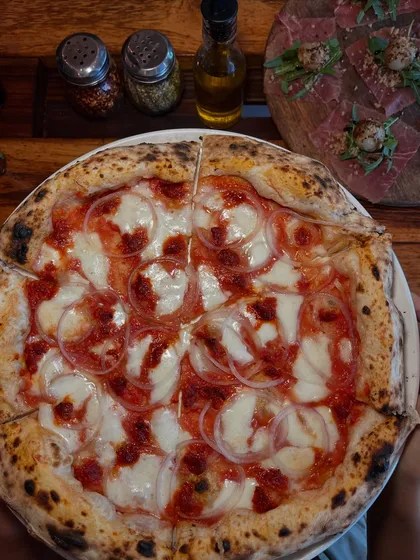 Another angle of our Goan Sausage pizza, with our house-made chili oil and other condiments in the background.