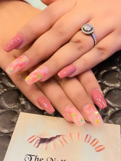 A lovely set of long, square nails in a dusty rose color. The accent nails feature a subtle, abstract design with small star glitter for a touch of whimsy.