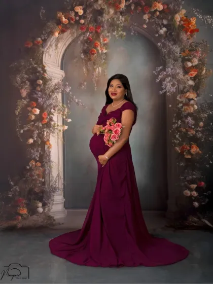 A stunning solo portrait in a deep magenta gown. The floral archway frames her beautifully, creating a rich and romantic image.