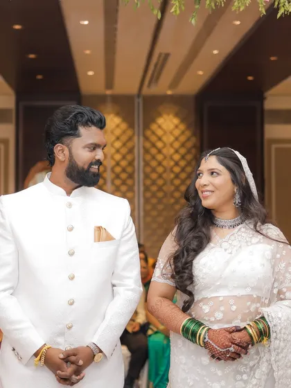 The bride and groom share a look during their ceremony. Her makeup is understated and elegant, perfect for her white saree.
