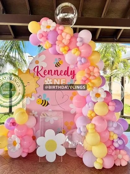 A "Fun to Bee One" party with a sunny, cheerful theme. The pink, yellow, and purple balloons are accented with cute bee and daisy cutouts.