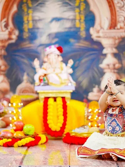 A moment of pure innocence as a little girl, dressed for the festival, looks up with her hands joined in a prayerful gesture.