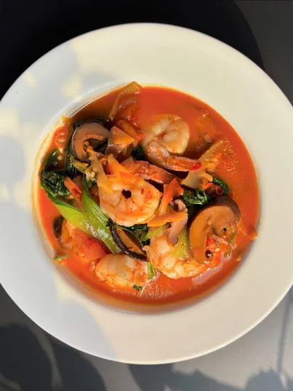 A Naga-style Prawn and Mushroom dish. The prawns and mushrooms are cooked in a light, oil-free broth with bamboo shoot extract and herbs, creating a simple yet deeply flavorful curry.