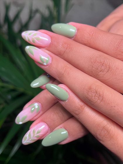A closer look at the nature-inspired nail art, with delicate white leaf patterns over a soft pink and green base.