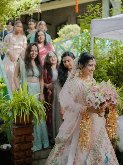 The bride's entrance with her bridesmaids, walking down a garden path holding a beautiful bouquet.