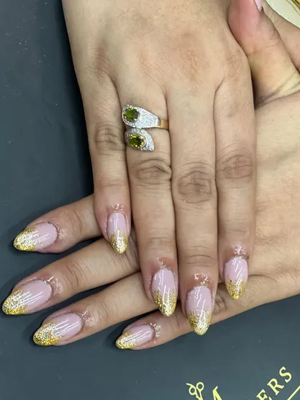 A detailed shot of the gold glitter fade manicure, focusing on the texture and sparkle of the glitter against the smooth, glossy base. This design is a popular choice for its blend of glamour and sophistication.