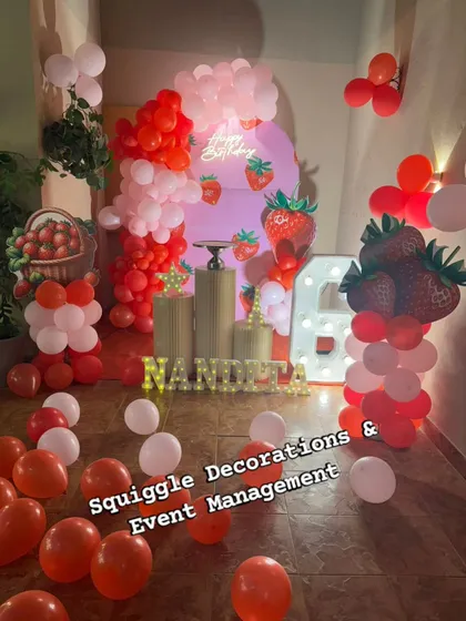 A sweet strawberry-themed birthday decoration. This unique setup uses red and pink balloons, strawberry cutouts, and a custom backdrop for a fresh and fun party.