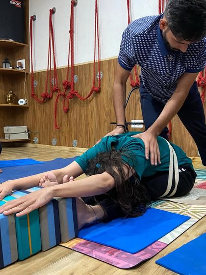 Here I am assisting a student in a seated forward bend (Paschimottanasana). By applying gentle pressure on the back, I help her lengthen her spine and fold deeper from the hips.