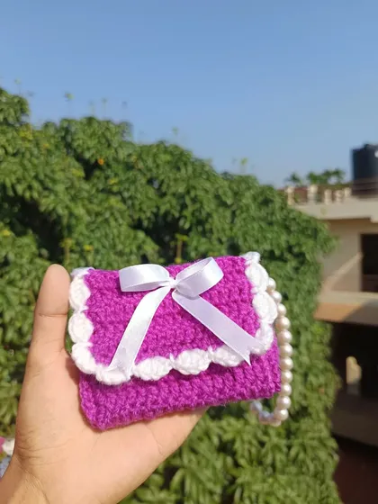 Holding the purple mini purse to show its compact and cute size. It's perfect for carrying small items in style.