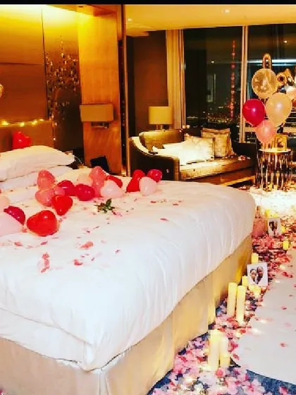 A complete romantic room transformation for a special anniversary. I used a trail of rose petals and flameless candles leading to the bed, which is decorated with heart-shaped balloons and a 'LOVE' foil banner for a truly memorable surprise.