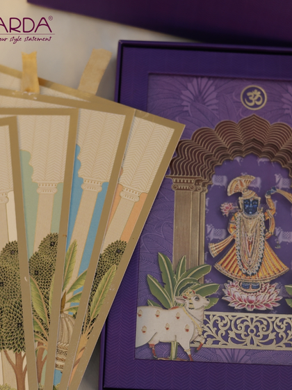 A closer look at the exquisite details of our Shreenathji-themed invitation. This view highlights the multi-layered papercraft, the sacred 'Om' symbol, and the accompanying illustrated inserts that complete this divine wedding suite.