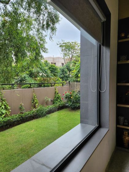 A view from inside the villa, where a large window perfectly frames the lush green garden. This highlights our design approach of creating a strong visual and physical connection between the interior living spaces and the natural landscape outside.