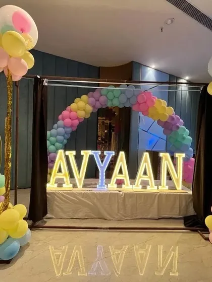 A Cocomelon themed birthday party with a large marquee name display and a colorful balloon arch.