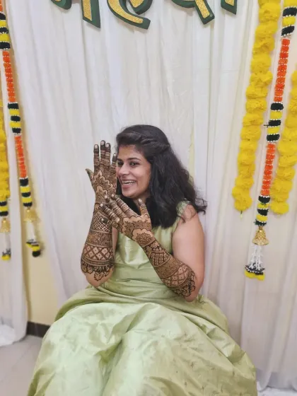 A happy bride enjoying her mehendi ceremony, her hands adorned with a classic and intricate traditional design.
