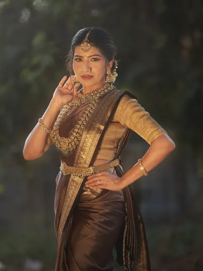 A powerful and poised stance from our traditional saree shoot. The soft, diffused outdoor lighting beautifully illuminates the model and the intricate details of her bridal attire.