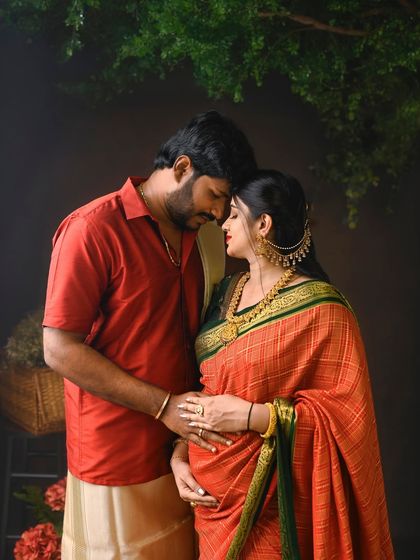 An intimate and heartfelt pose during a South Indian traditional maternity shoot. The rich colors of the saree and the traditional jewelry add to the beauty of the moment.