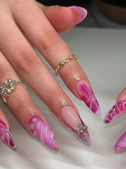 A vibrant and textured design. These long stiletto nails feature a pink and purple marble effect with 3D textures and silver rhinestone accents.