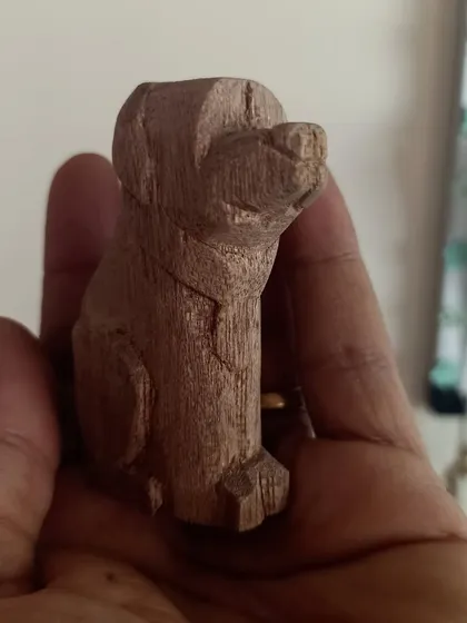 Another angle of the whittled dog, highlighting the facets and tool marks that give hand-carved objects their unique charm.