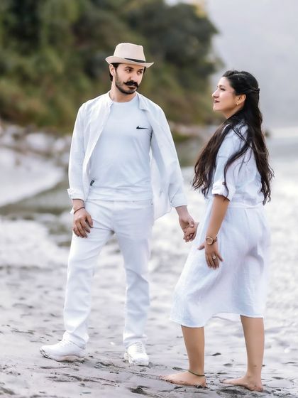 A stylish pose on the riverbank, with the couple dressed in coordinated white outfits. This shot has a clean, modern, and fashionable feel.