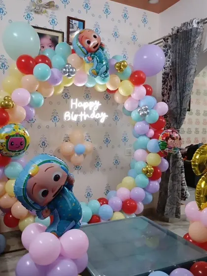 Another angle of the Cocomelon party, showing the "Happy Birthday" neon sign and the number '2' foil balloon.