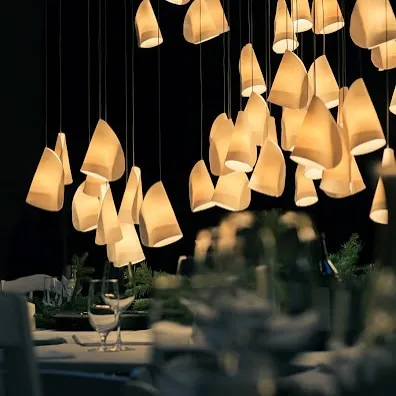 A beautiful installation of the Bocci 21 series over a dining table. Each thin porcelain shade is shaped by hand, creating a unique, organic form that emits a soft, warm light.