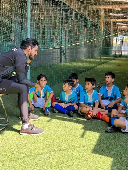 A quiet moment of mentorship. A coach sits down with our youngest players to explain a concept and build their understanding.