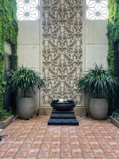 This serene courtyard was part of our set design. We used two large dracaenas in polymer pots to frame the intricate wall panel, creating a symmetrical and peaceful look.