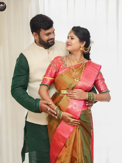 A studio portrait of a couple during their maternity session. The clean, high-key background puts all the focus on their interaction and the traditional attire.
