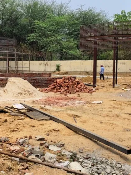 A wider view of the school landscape site, with brickwork for planters and the framework for pergolas being set up.