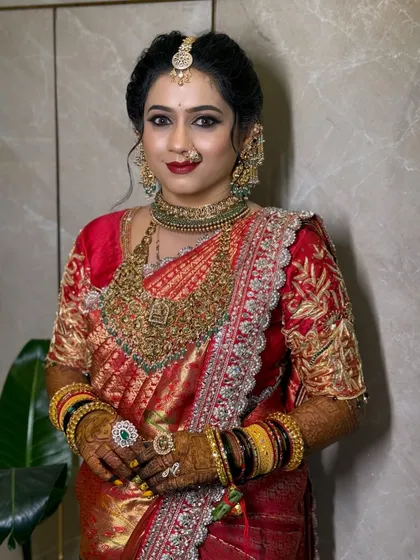 A beautiful bride in a red and gold Kanjeevaram, her makeup perfectly complementing her attire.