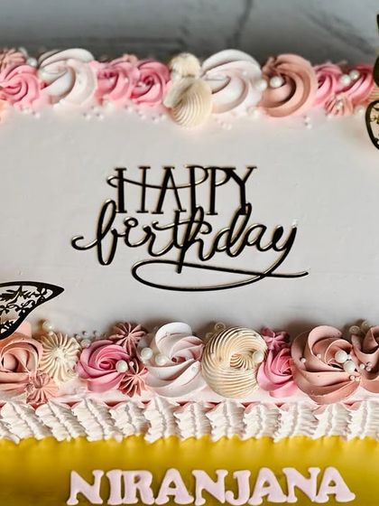A beautiful and trendy sheet cake with pink and white rosettes and elegant butterfly accents.