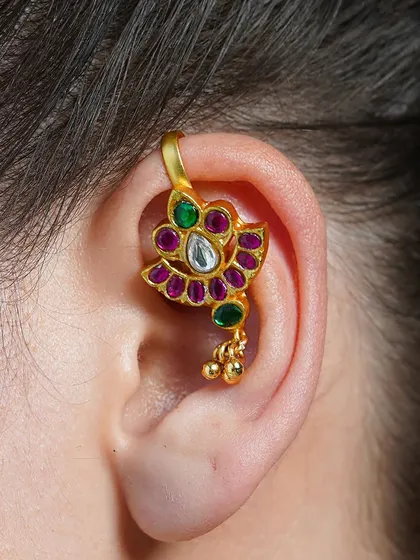 A close-up of our Alayaa earcuff, featuring a peacock-inspired design with ruby and emerald colored stones. A small detail that makes a big impact.