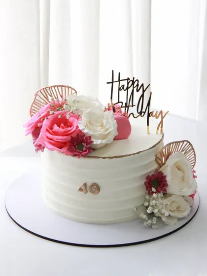 A simple yet beautiful 40th birthday cake. The textured white ganache is adorned with fresh flowers and rose gold accents for a modern and chic look.