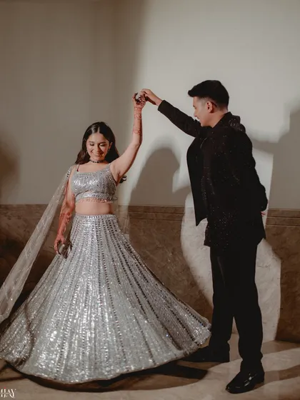 A joyful moment on the dance floor as the groom twirls his bride in her sparkling silver lehenga.