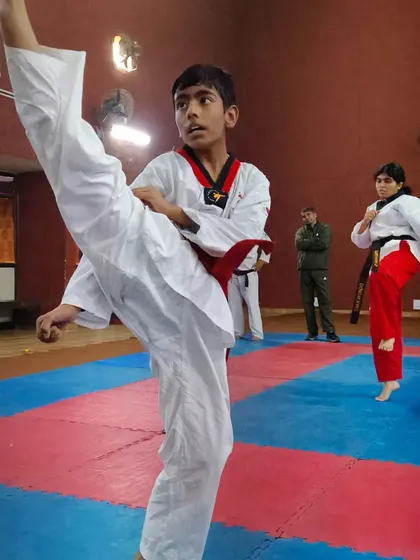 A young Taekwondo student practices a high side kick, showing great form and focus. I train students of all ages to develop proper technique.
